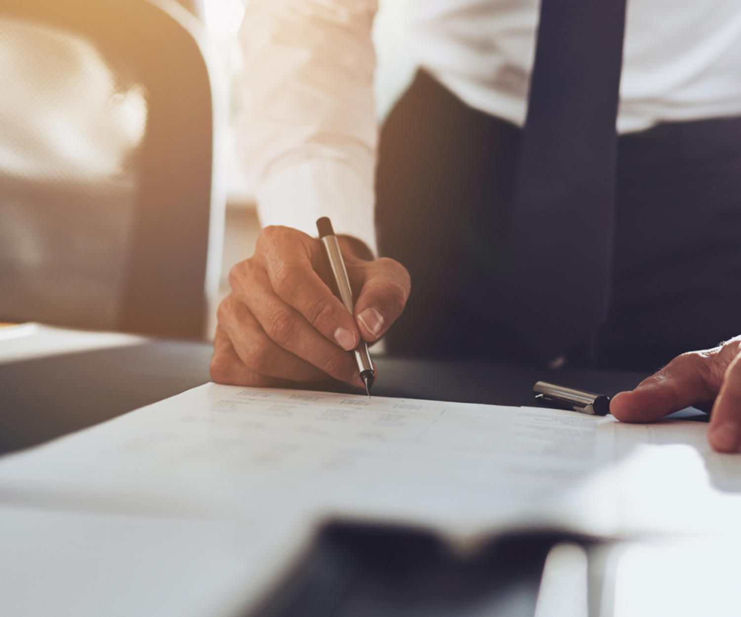 Mann im Anzug schreibt etwas auf Papier