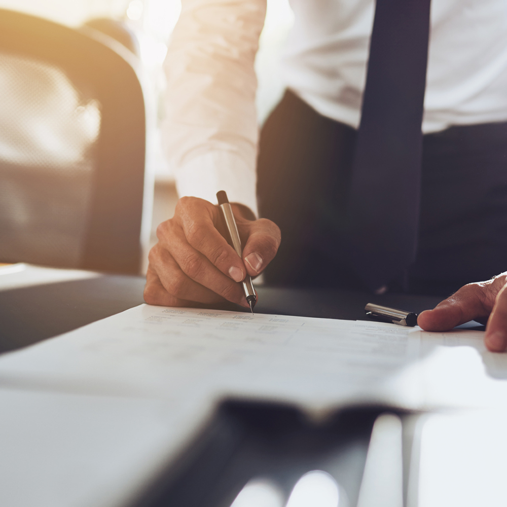 Mann im Anzug schreibt etwas auf Papier